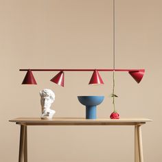 a table with three different colored lamps hanging from it's sides and a vase on the other side