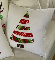 two pillows with christmas trees on them sitting next to each other in front of a couch