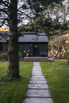 a path leading to a small cabin in the woods with trees and grass on either side