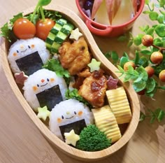 a wooden bowl filled with sushi and vegetables on top of a table next to other foods