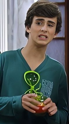 the young man is holding a green alien toy