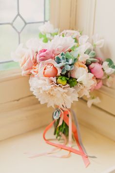 a bouquet of flowers sitting on top of a window sill next to a ribbon