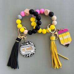 two bracelets with tassels and charms attached to them on a gray surface