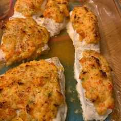 four pieces of fish fillet in a glass dish on a wooden table with sauce