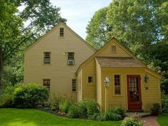 a small yellow house sitting in the middle of a lush green yard