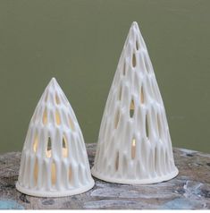 two white ceramic candlesticks sitting on top of a wooden table next to each other