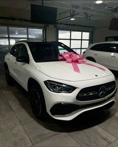 a white mercedes car with a pink bow on it's hood in a showroom