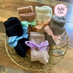 several different colored towels are on a wire basket with a bow around the edge and add on sticker