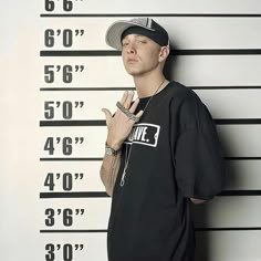 a man standing in front of a mugshot wall with his hand up to the side