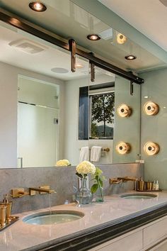 a bathroom vanity with two sinks and gold faucets on the mirror above it