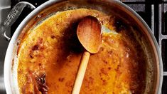 a wooden spoon in a pot filled with food on top of an oven burner