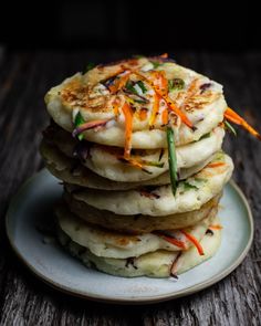 a stack of food sitting on top of a white plate next to a wooden table