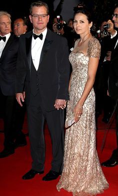 two people in formal wear standing on a red carpet