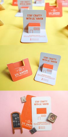 some orange and white business cards on top of a yellow table with a cell phone