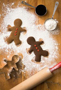 three gingerbread cutouts sitting on top of a table next to cookie cutters