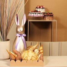 a table topped with cakes and bunnies next to a vase filled with strawberries