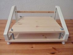 a wooden step stool sitting on top of a hard wood floor next to a white wall