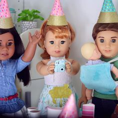 three dolls wearing party hats and one holding a camera, the other taking a photo