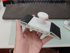 a hand holding a white and black object on top of a table