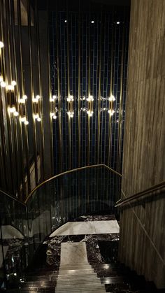 the stairs are made of marble and have lights hanging from them over them, along with glass railings