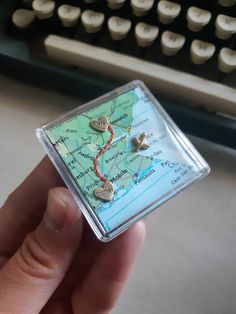 a person holding a tiny map in front of a typewriter with keys on it