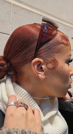 a woman with red hair and piercings on her ear