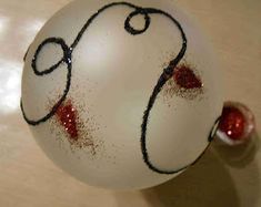 a white ornament with red and black paint on it's face is sitting on a table