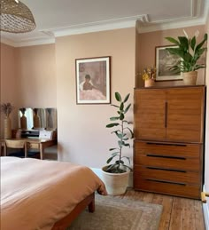 a bed room with a neatly made bed and a plant on top of the dresser