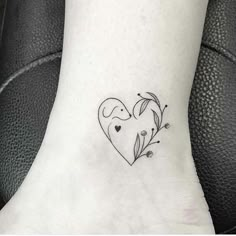 a small heart tattoo on the ankle with flowers and leaves around it's edges