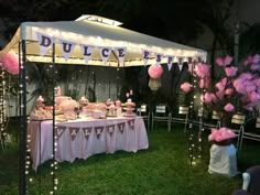 a table with pink flowers and lights under a tent