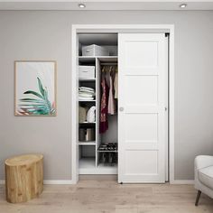 an open white closet with clothes hanging on the door and a chair next to it