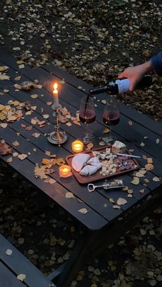 a table that has some food on it with candles and wine glasses in the background