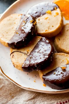 chocolate covered donuts on a plate with sprinkles and orange zest