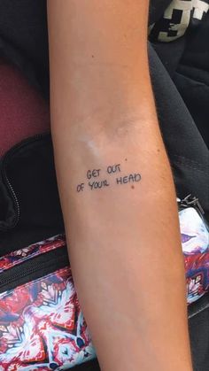 a woman's arm with the words get out of your head written on it