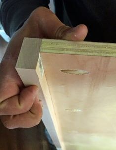 a person holding a piece of plywood in their left hand and the other hand on top of it