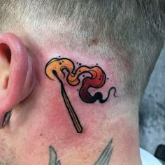 a man's neck tattoo with scissors and a snake on top of his head