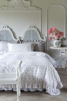 a white bed sitting next to a table with flowers on it