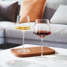 two glasses of wine sitting on top of a table next to each other in front of a couch