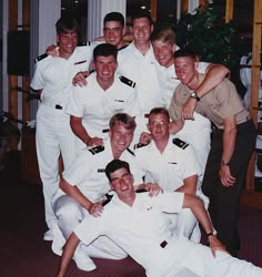 a group of men in white uniforms posing for a photo together with one man holding his arm around the other's neck