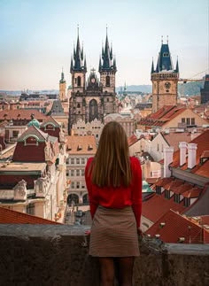 a woman standing on top of a building looking at the cityscape in prague