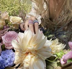 a woman sitting in front of a bunch of flowers with her wedding ring on her finger