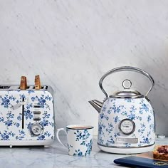 two blue and white toasters sitting on top of a counter next to a cup