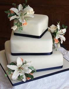 three tiered wedding cake with white flowers on the top and black trimmings