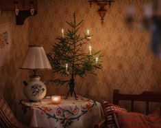 a small christmas tree sitting on top of a table next to a lamp and chair