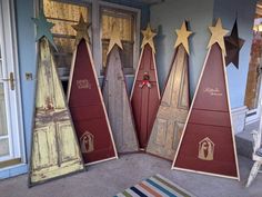 three wooden christmas trees sitting next to each other on top of a rug in front of a door