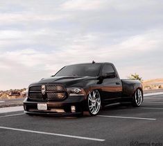 a black truck parked in a parking lot next to a road with no cars on it