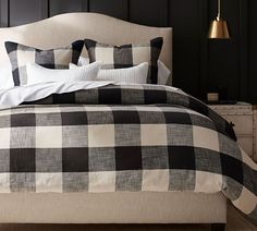 a bed with black and white checkered comforter, pillows and blankets on it