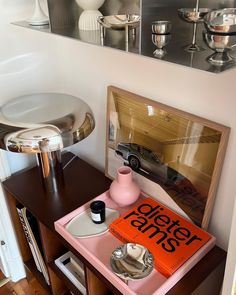 a pink tray with an orange book on it next to a mirror and lamp in a room