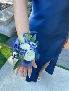 a woman wearing a blue dress holding a bouquet of white and blue flowers in her hand