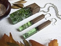 three pieces of green glass sitting on top of a table next to leaves and an apple